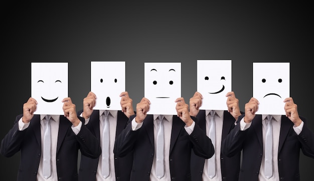 Five businessman holding a card with drawing facial expressions different emotion feelings face on white paper Premium Photo