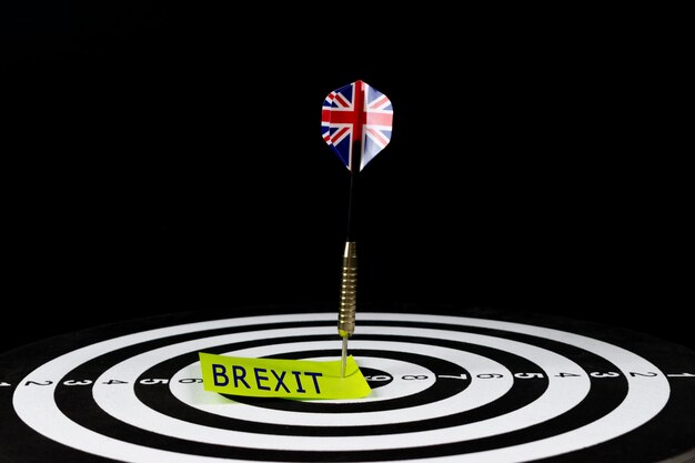 Flag of uk dart arrow hitting in the target center of dart board with text Premium Photo