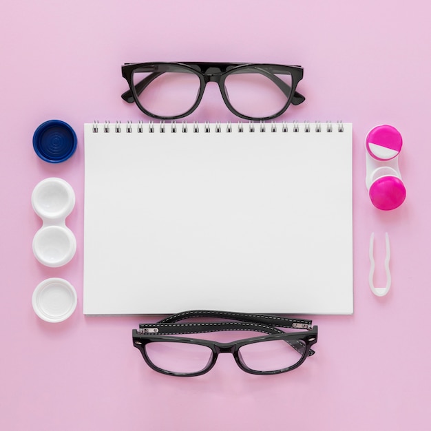 Flat lay eye care accessories on pink background with notebook mock-up Free Photo
