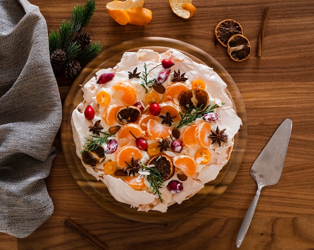 Flat Lay Of Meringue Cake Decorated With Orange Slices And Rosehip