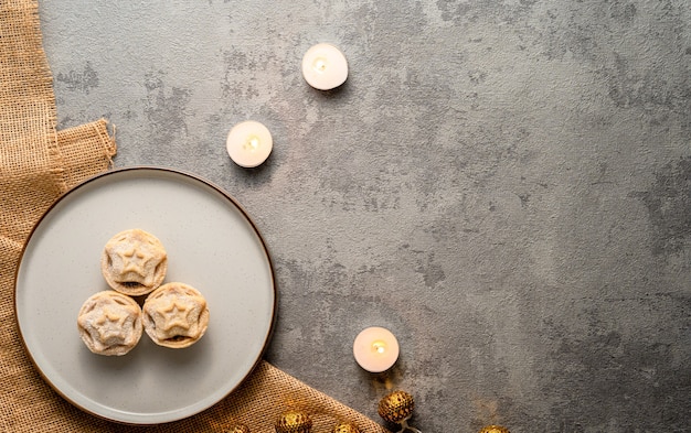 Free Photo | Flat lay of mince pies served on a dish and burning candles