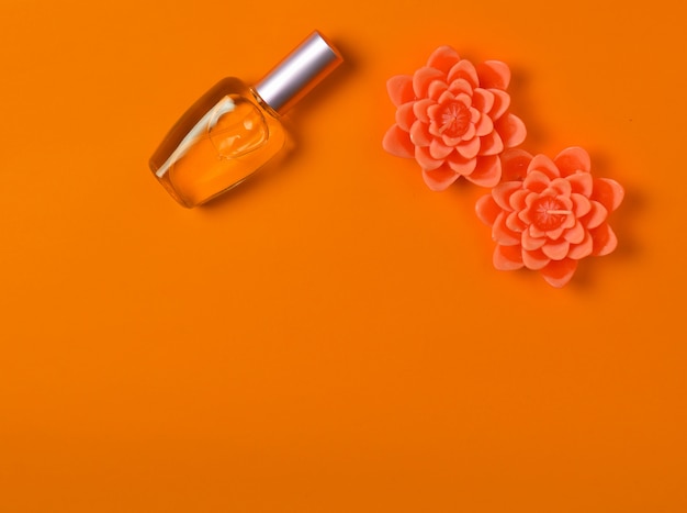 香水瓶とオレンジの花の形のキャンドルのフラット横たわるミニマリズム プレミアム写真