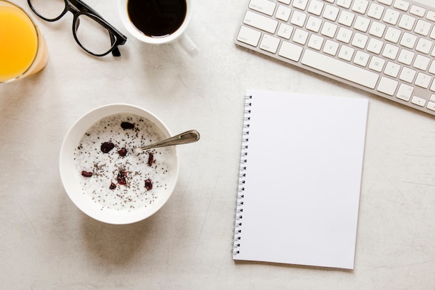 Flat lay notebook and bowl with yogurt raisins and chia seeds Free Photo