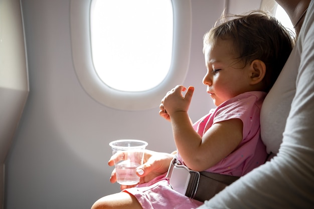 Premium Photo Flight With Infant Toddler Sits On Mom S Lap Fastened With A Special Belt In Airplane Before Porthole