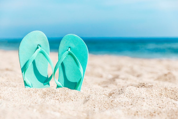 Premium Photo | Flip flops stuck in the sand on a sandy beach by the ...