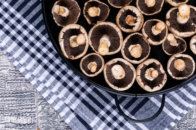 灰色の木製のテーブルにピクニック布の上面に鍋に白いキノコを反転 無料の写真