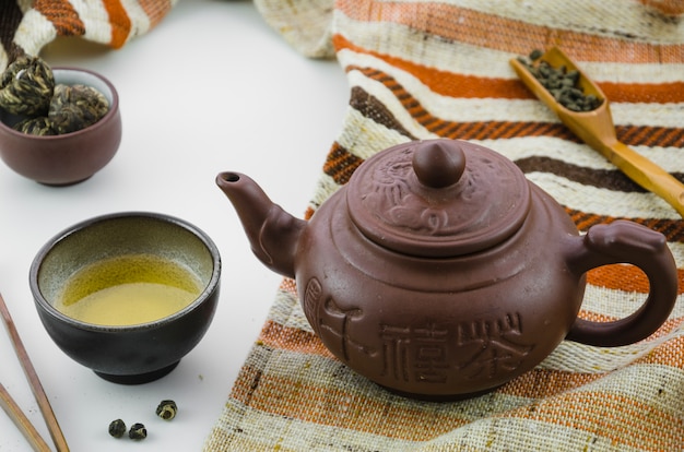 Floral blooming tea ball and oolong tea dust tea against white background Free Photo