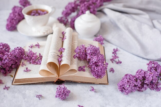 咲くライラックと花びらの枝を持つ古フランス語の本の折り畳まれたページ プレミアム写真