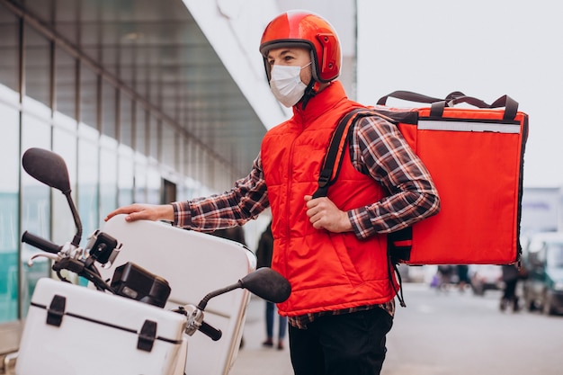 Food delivery boy driving scooter with box with food and wearing mask Free Photo