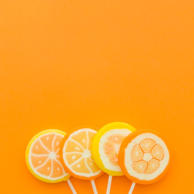 オレンジ色の背景の下にある4つの柑橘類の果物棒 無料の写真