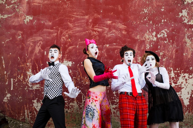 Premium Photo | Four mimes in fear stand in the background of a red wall.