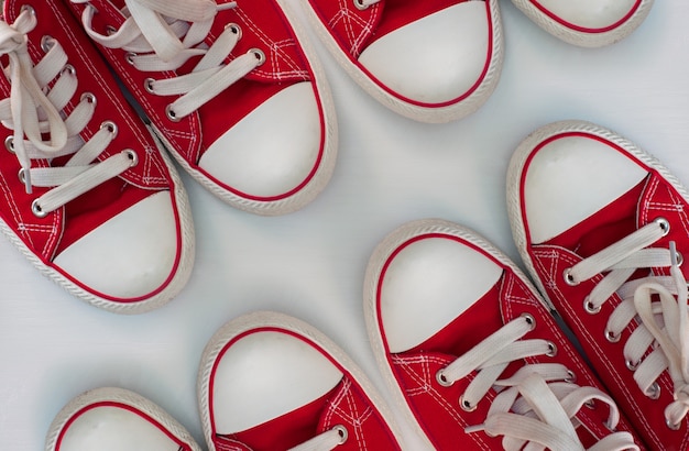 Four pairs of red sneakers on a white wooden surface Premium Photo