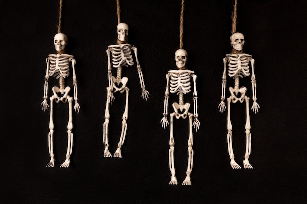 4つのおもちゃの吊るされた骸骨は平らに暗い背景を置きました プレミアム写真