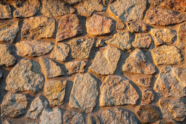 Premium Photo | Fragment of sunlit stone wall at sunset. front view