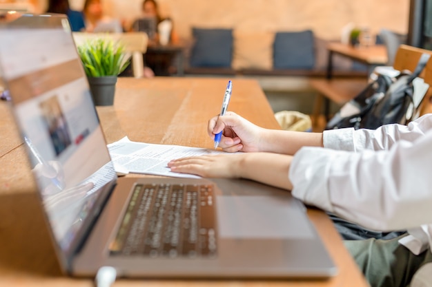 Freelancer filling document form with laptop open on wooden table. Premium Photo