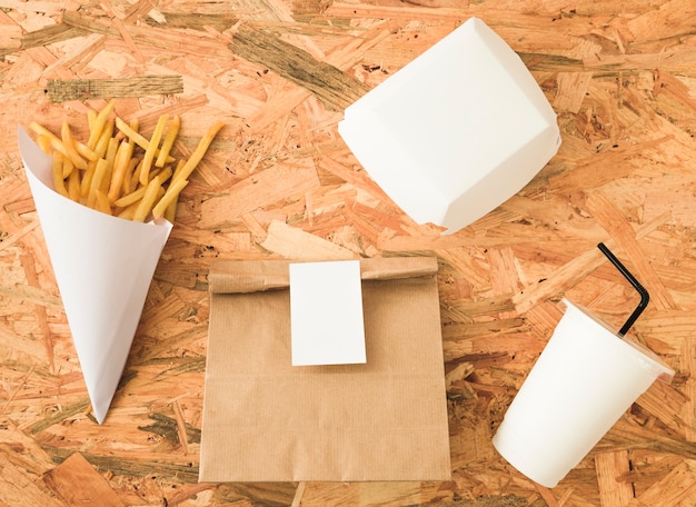 Download French fries in paper cone and package mockup on wooden backdrop | Free Photo