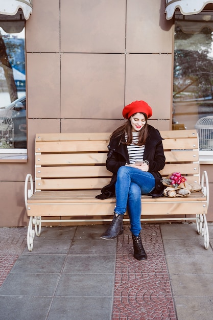 Free Photo | French woman in a red beret on a street bench