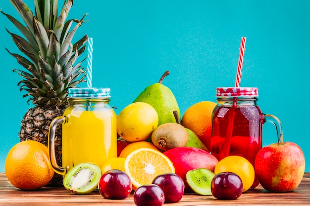 Frascos de pedreiro de frutas e suco saudÃ¡veis â€‹â€‹frescos na mesa contra o fundo azul Foto gratuita