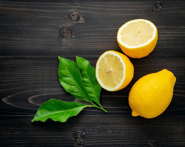 Premium Photo | Fresh lemons and lemons leaves on dark wooden background.