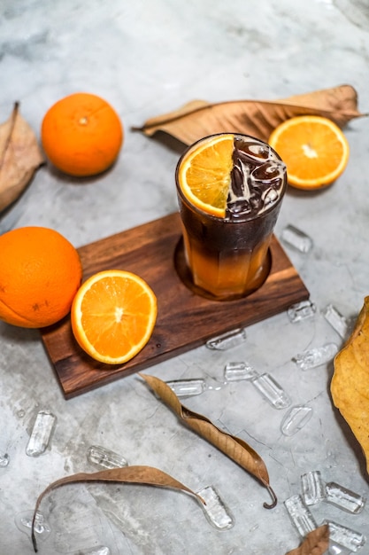 フレッシュオレンジジュースと柑橘系の果物ビタミンcには 新鮮でフレーク状の甘い 木製のトレイ 葉 丸い角氷に並べられた健康上の利点があります プレミアム写真