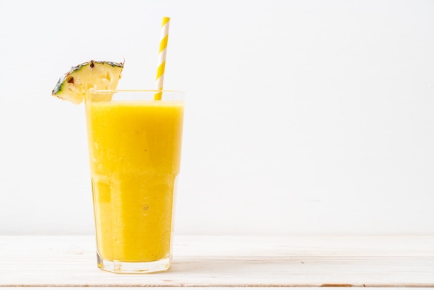 Fresh pineapple smoothie glass on wood table Premium Photo
