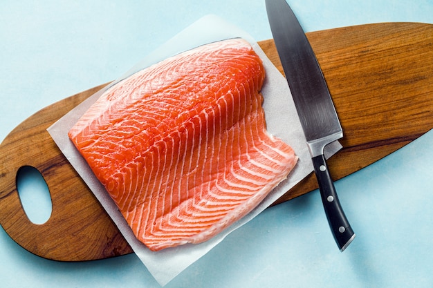 Fresh salmon slice on a wooden cutting board with a chef's knife on the ...