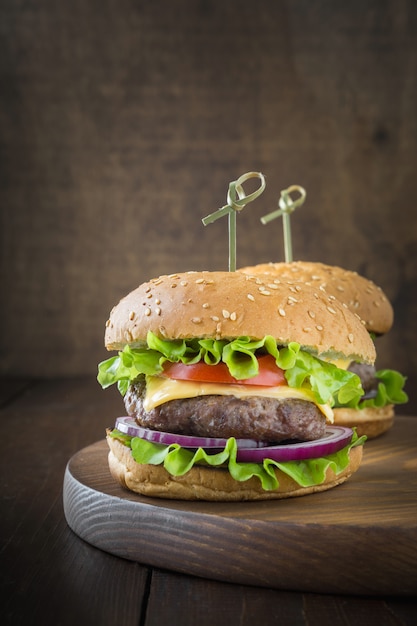 Fresh two beef burgers with vegetables on wooden board. party. vertical ...