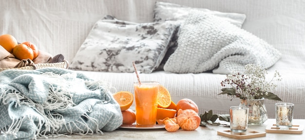 Freshly-grown organic fresh orange juice in the interior of the house, with a turquoise blanket and a basket of fruit Free Photo