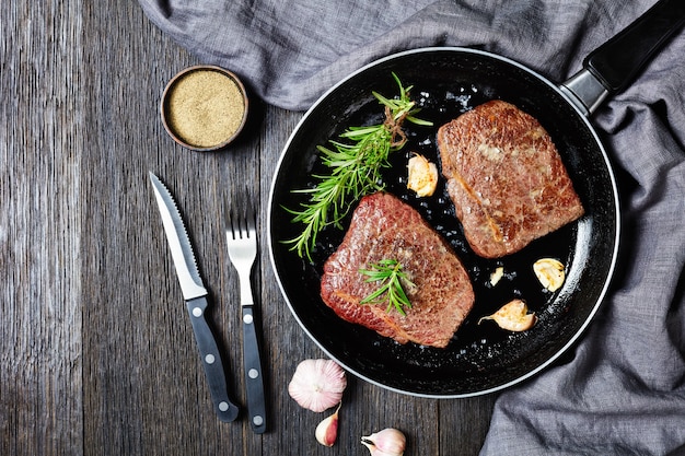 Premium Photo | Fried beef steaks with rosemary bouquet, garlic and ...