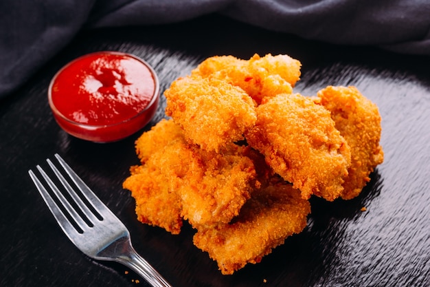 Premium Photo | Fried chicken on a black background and ketchup on the side