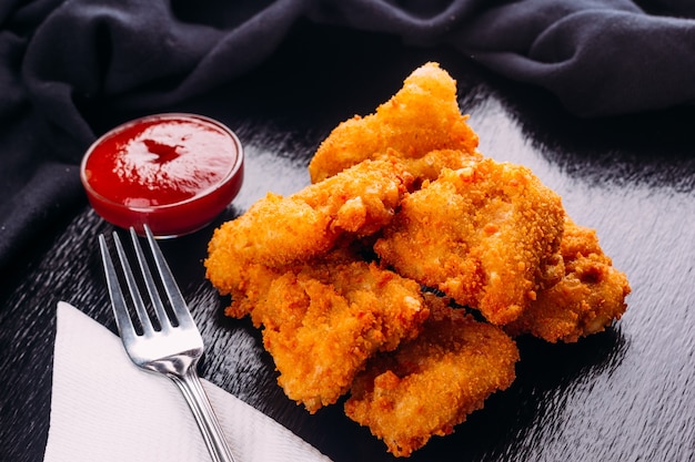 Premium Photo | Fried chicken on a black background and ketchup on the side