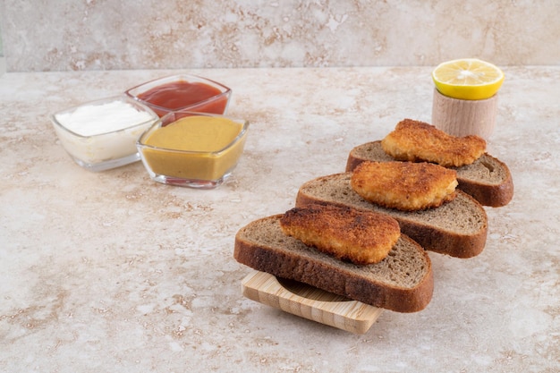 Free Photo | Fried chicken nuggets on dark bread slices served with sauces.