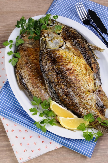 Premium Photo | Fried crucian carp in a plate on the table with napkins