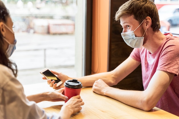 Friends chatting while wearing medical masks in a pub Free Photo