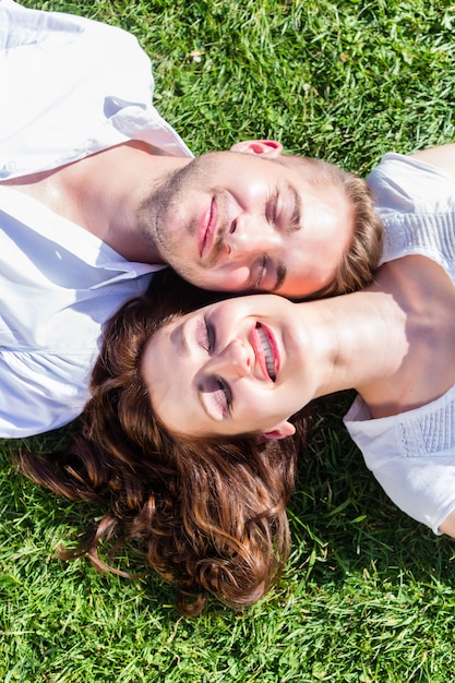 Premium Photo | Friends laying side by side on park lawn enjoying sun