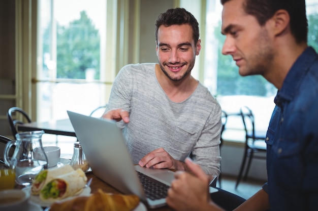 Free Photo | Friends sitting at table and using laptop in cafã©