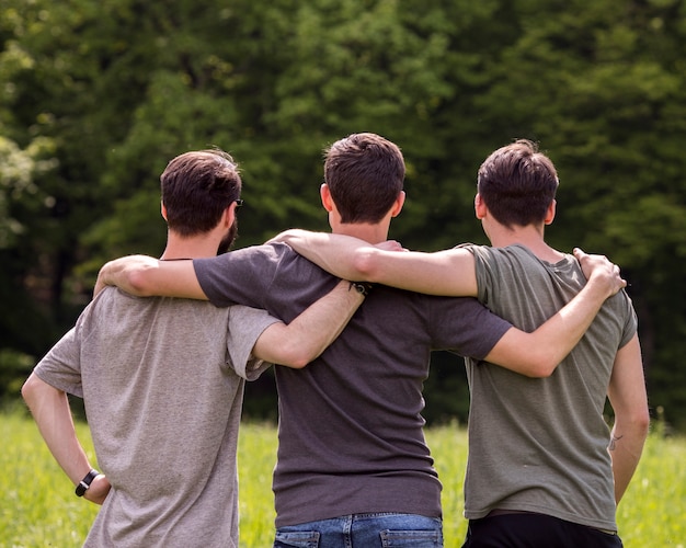 Free Photo | Friends standing on glade with hands on each other shoulders