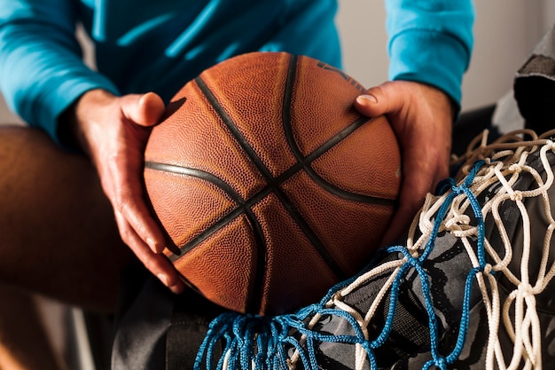 Download Front view of basketball on top of net held by man wearing hoodie | Free Photo