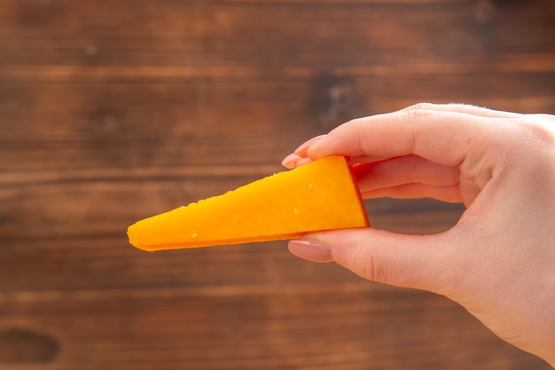 Free Photo | Front view cheese in female hand on brown isolated surface