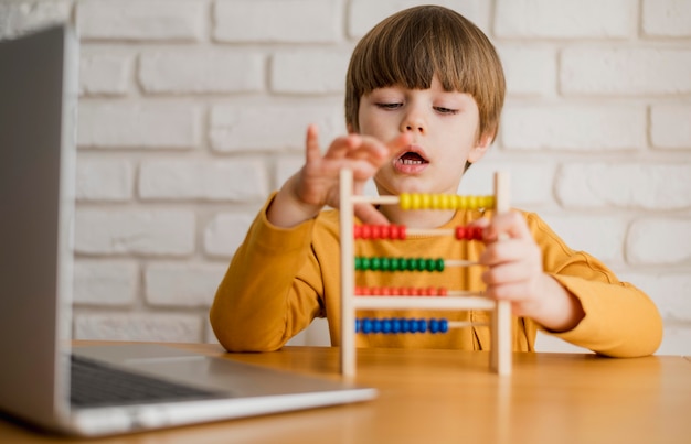 Front view of child using abacus with laptop | Free Photo