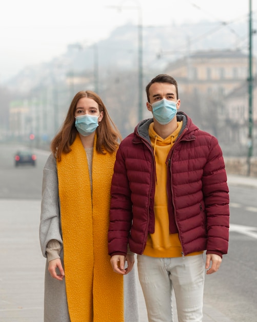 Free Photo | Front view of couple posing together with medical masks