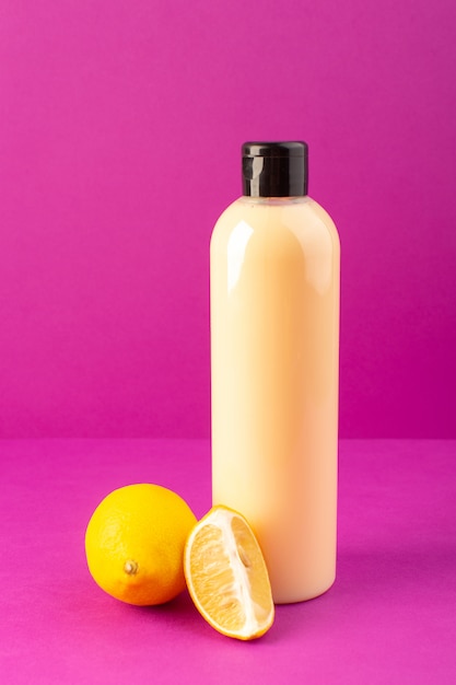 Download A front view cream colored bottle plastic shampoo can with black cap along with lemons isolated ...