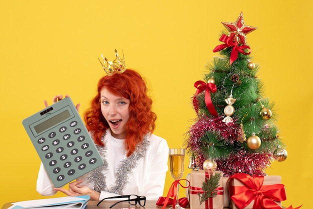 Front view female doctor holding calculator around xmas presents and tree Free Photo