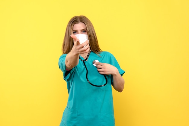 Free Photo Front View Female Doctor Wearing Sterile Mask On Yellow Floor Emotion Medical Hospital