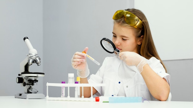 Free Photo | Front view of girl scientist with test tube and magnifying ...