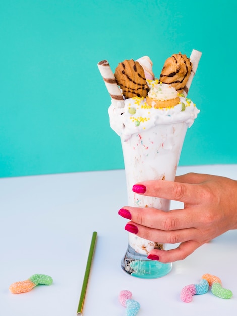 Front view of a hand holding a glass on milkshake Free Photo