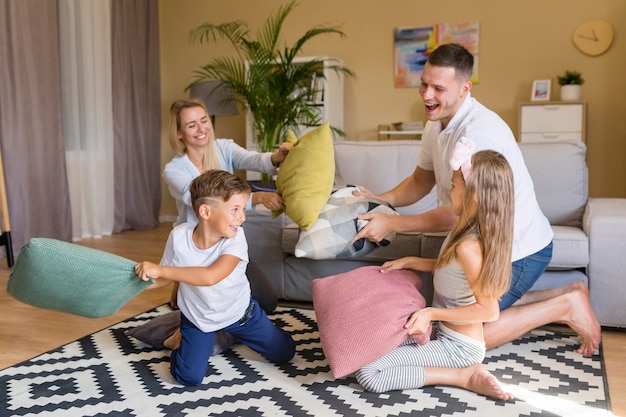 Front view happy family playing with pillows Free Photo