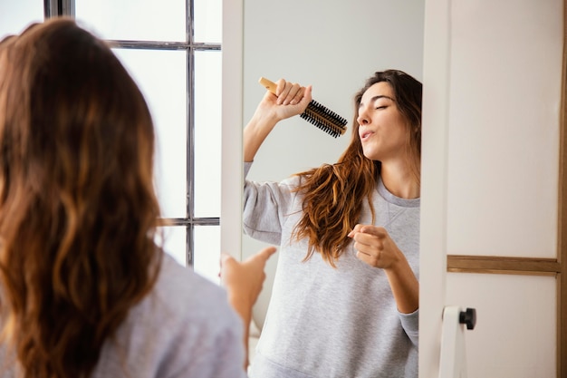 Free Photo | Front view of happy woman singing into hairbrush at home