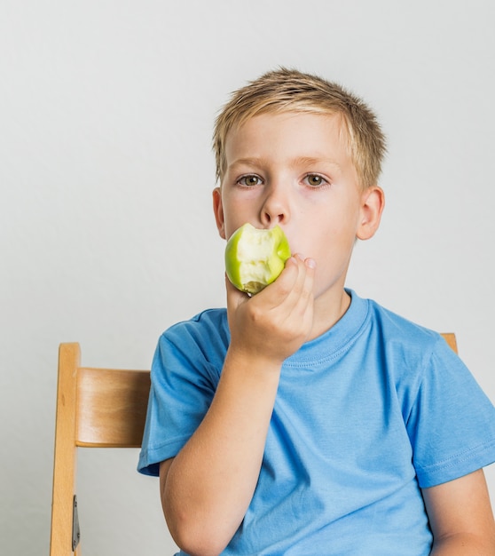 Front View Kid With Blonde Hair Bitting An Apple Photo Free Download