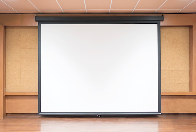 Front view of lecture room with empty white projector screen Free Photo